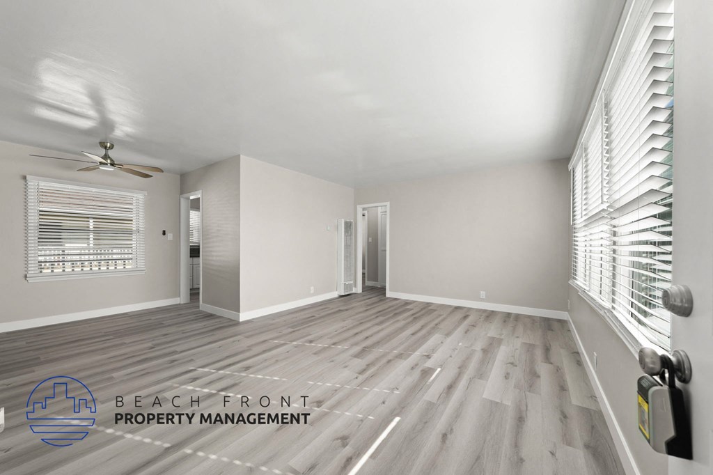 A spacious room with wooden flooring and a ceiling fan.