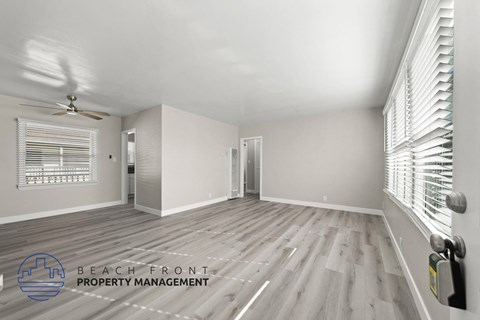 A spacious room with wooden flooring and a ceiling fan.