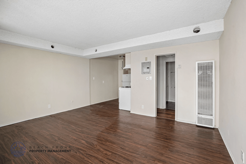 A spacious room with wooden floors and white walls.
