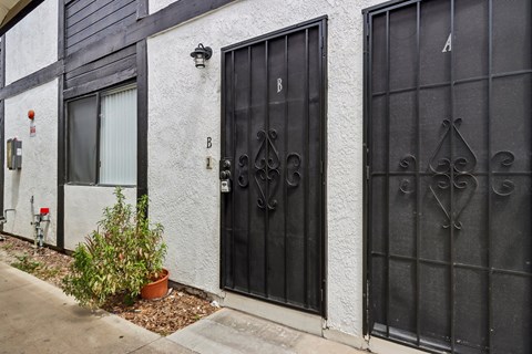 A black gate with a decorative design is on the right side of a white building.