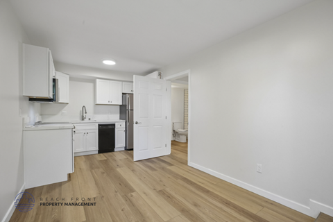 A kitchen with white cabinets and a wooden floor.