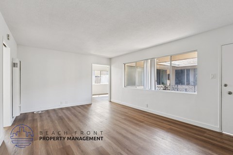 A spacious room with wooden floors and a large mirror on the wall.
