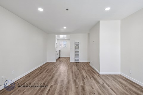 A spacious room with wooden flooring and white walls.