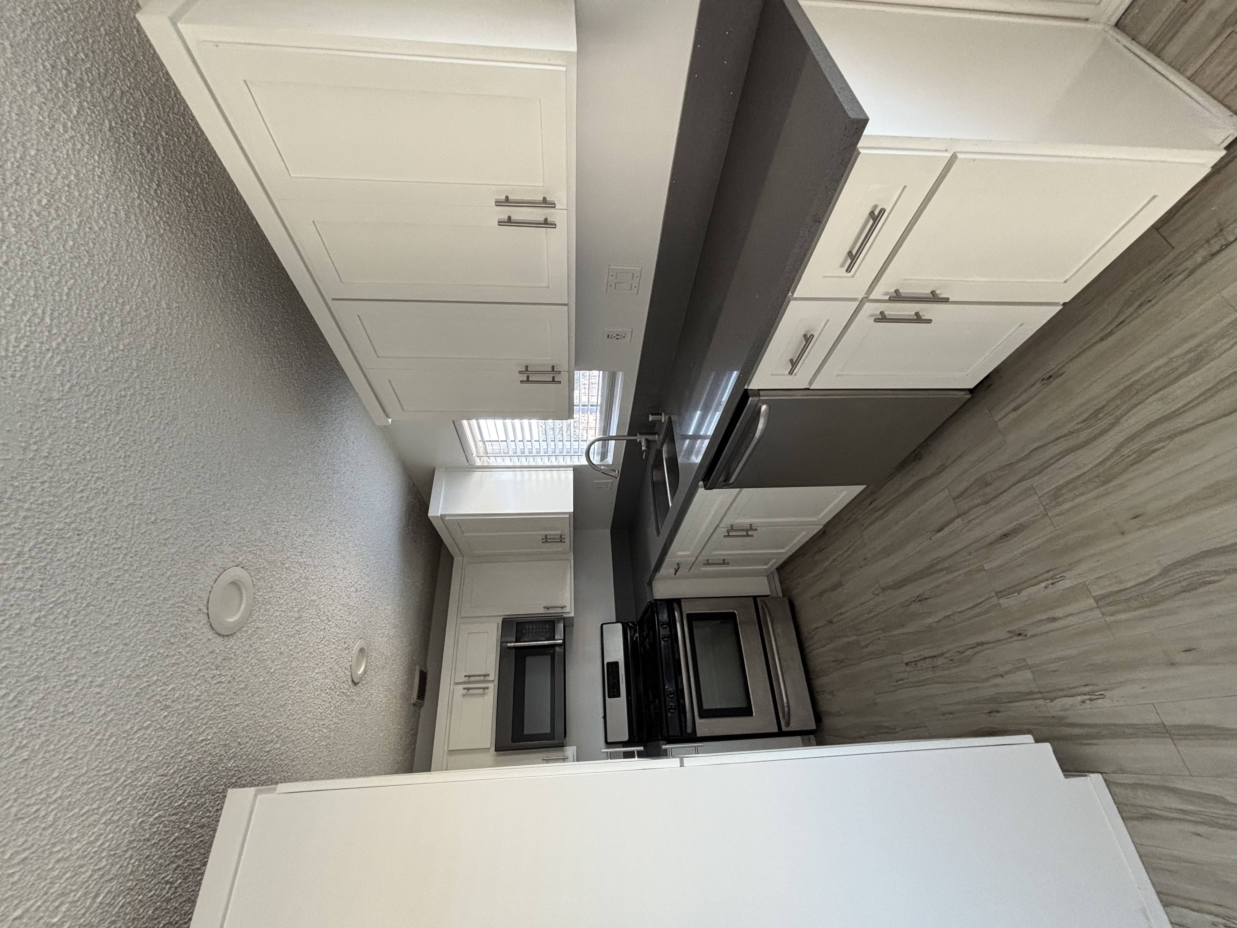 A kitchen with white cabinets and a white refrigerator.