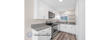 A kitchen with white cabinets and a stove top oven.