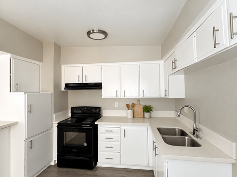 A black stove in a white kitchen with a sink.