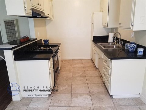 a kitchen with white cabinets and black counter tops