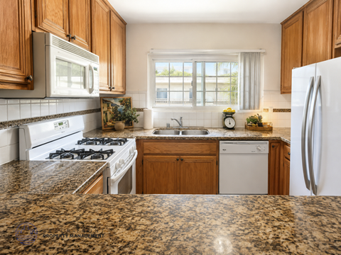 A kitchen with granite countertops and white appliances.