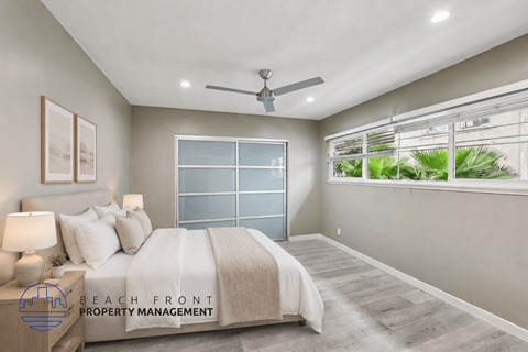A well-lit bedroom with a large bed and a ceiling fan.