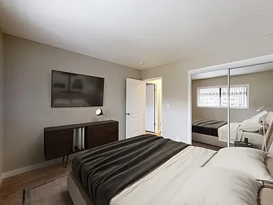 A bedroom with a large bed and a television on the wall.