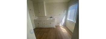 A kitchen with white cabinets and a wooden floor.