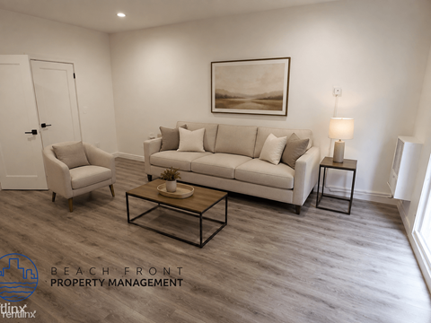 A living room with a white couch, a chair, and a coffee table.