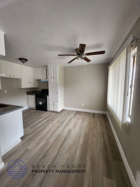 A spacious room with a ceiling fan and wooden flooring.