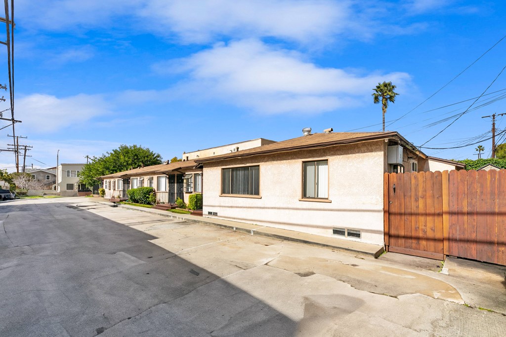 an empty street in front of a white house with a wooden fence