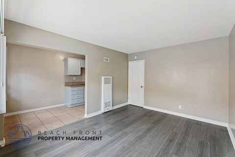 A spacious room with wooden flooring and a white door.