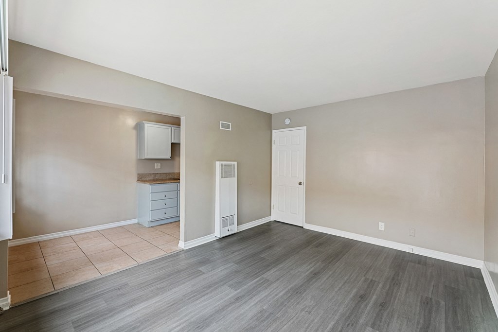 an empty living room with a door to a kitchen