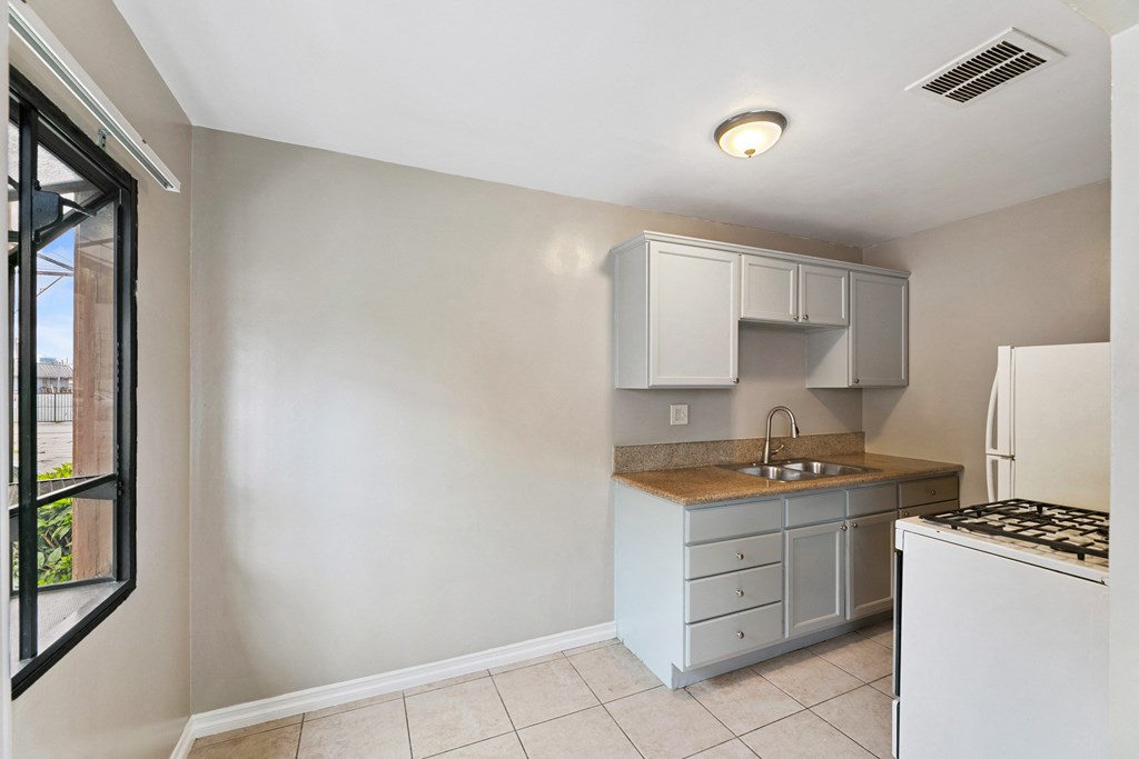 an empty kitchen with white cabinets and a window
