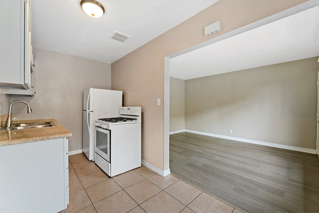 an empty kitchen with a stove and refrigerator and a sink