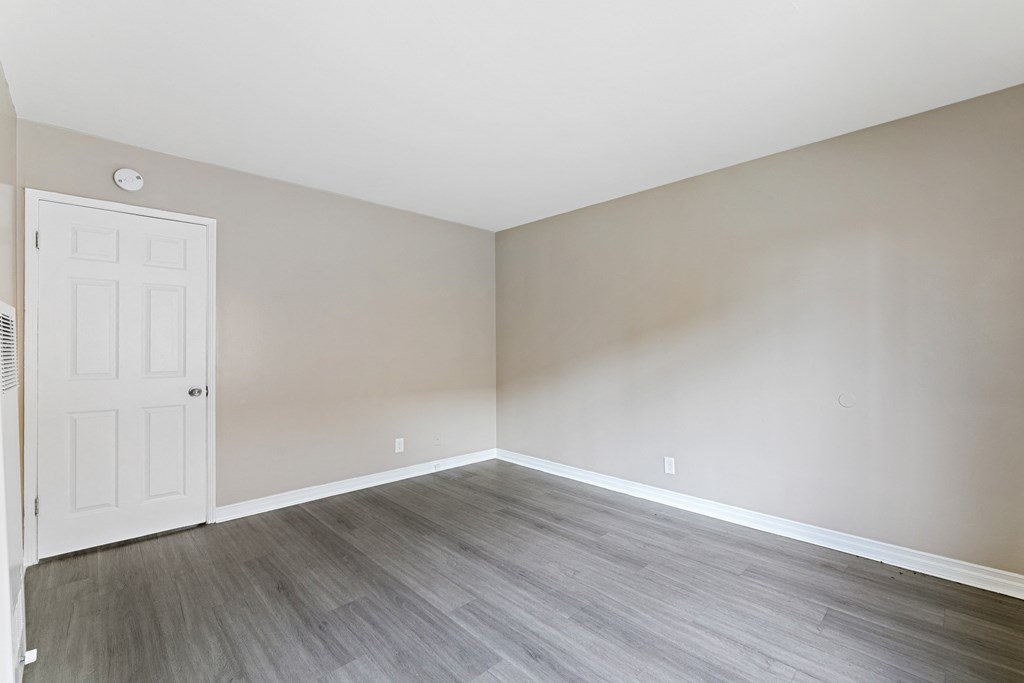 an empty room with wood flooring and a white door