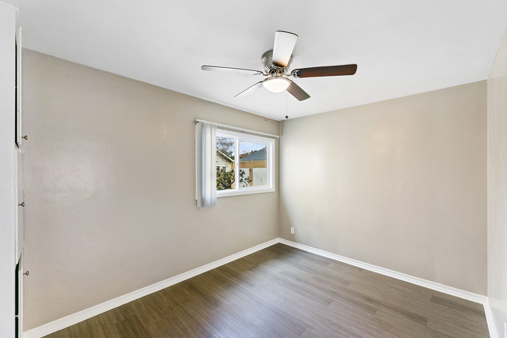an empty room with a ceiling fan and a window