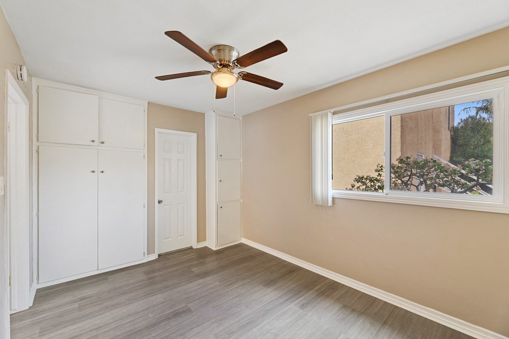 an empty bedroom with a ceiling fan and a window