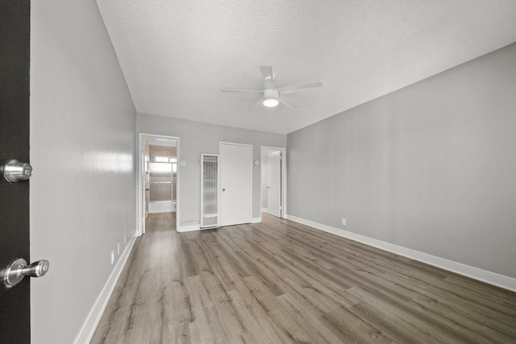 the living room of an empty house with wood flooring and a ceiling fan