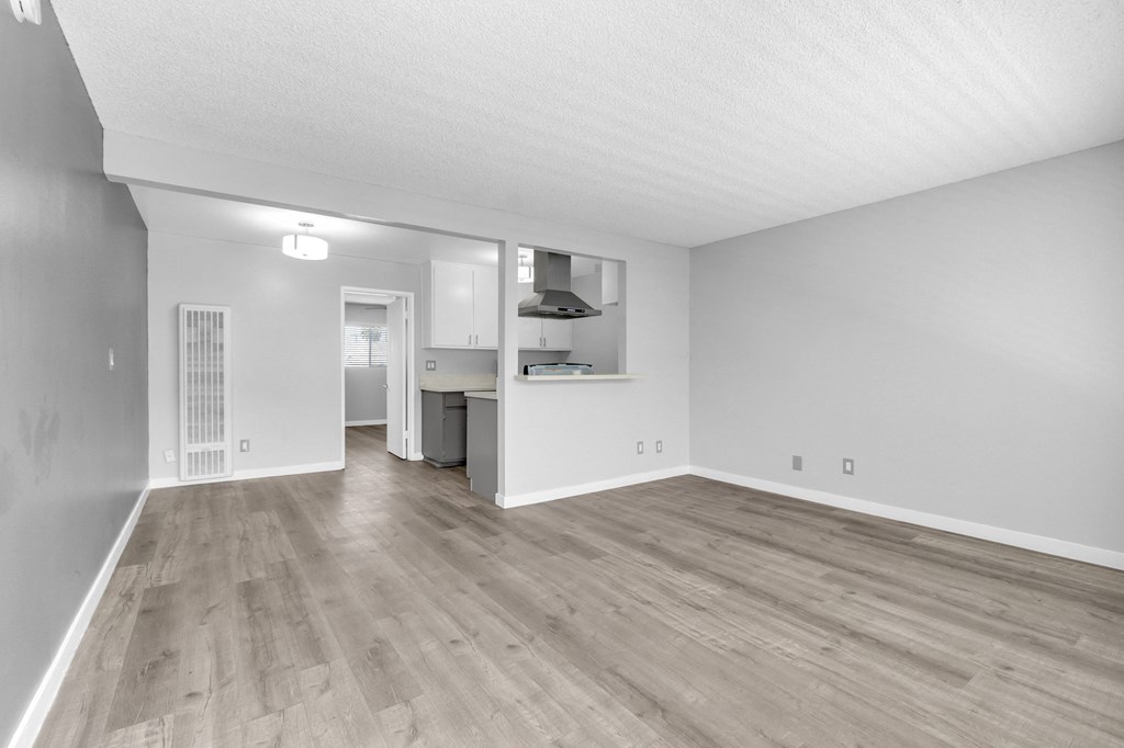the living room and kitchen of an apartment with wood flooring