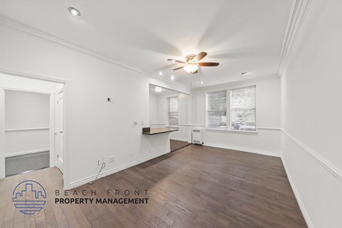 a living room with white walls and a ceiling fan