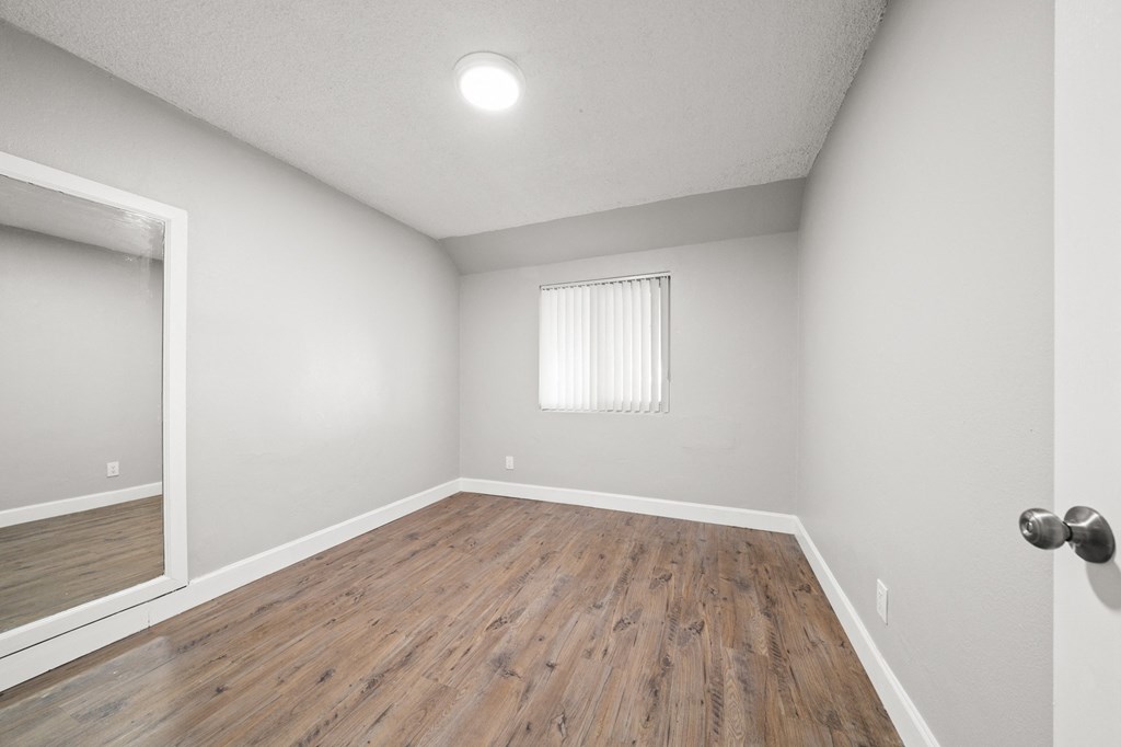 the living room of an apartment with wood flooring and a window