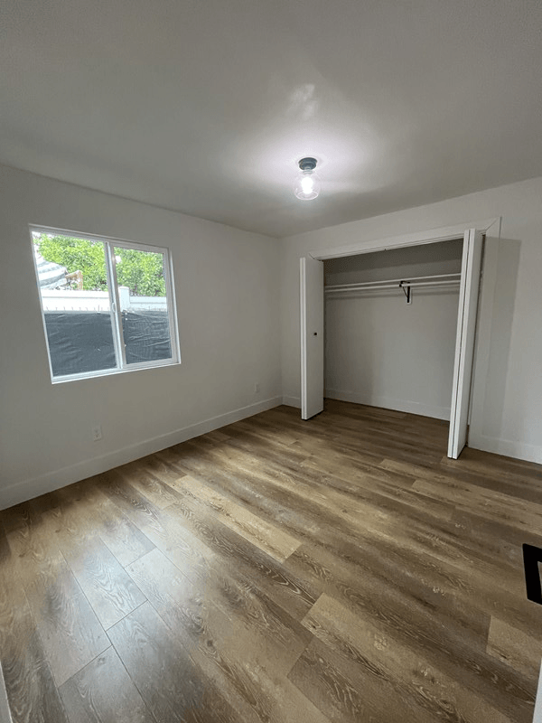 an empty bedroom with a large window and a closet