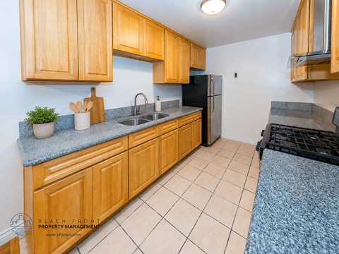A kitchen with wooden cabinets and a black fridge.