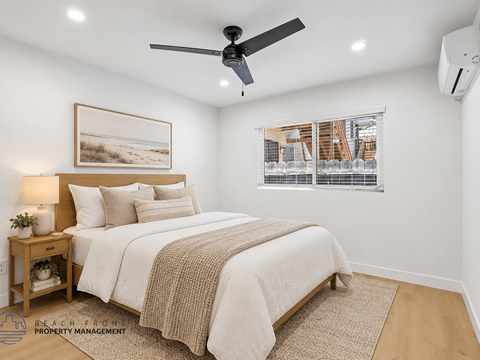 A bedroom with a bed, a ceiling fan, and a window with blinds.