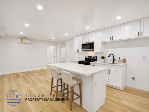 A kitchen with white cabinets and a wooden floor.