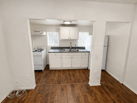 A kitchen with white cabinets and a wooden floor.