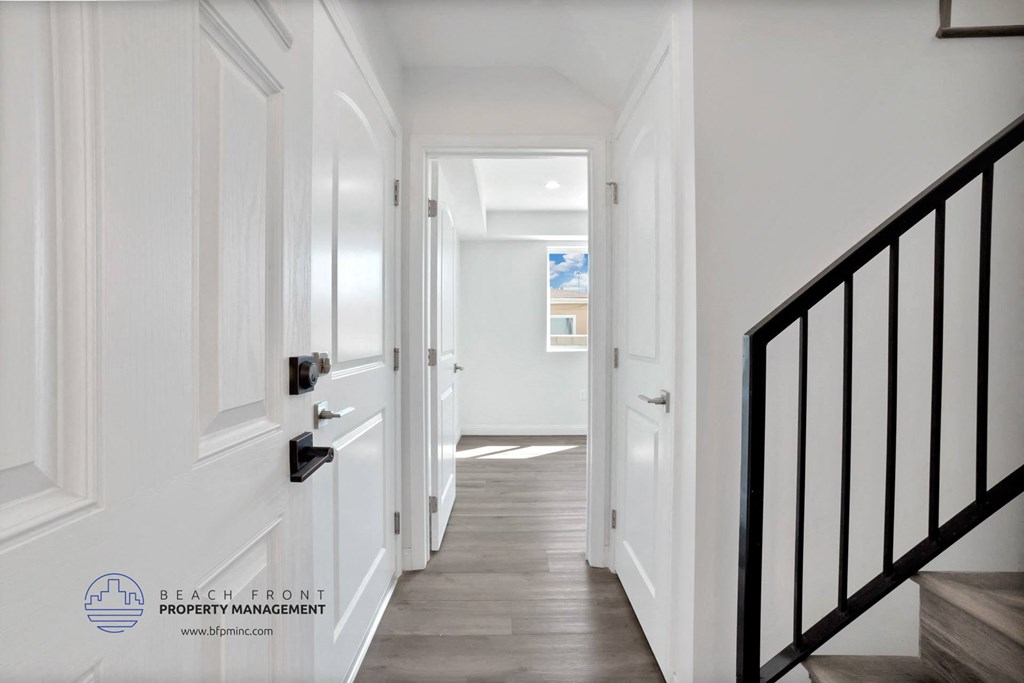 a white hallway with a staircase and white walls and wood floors