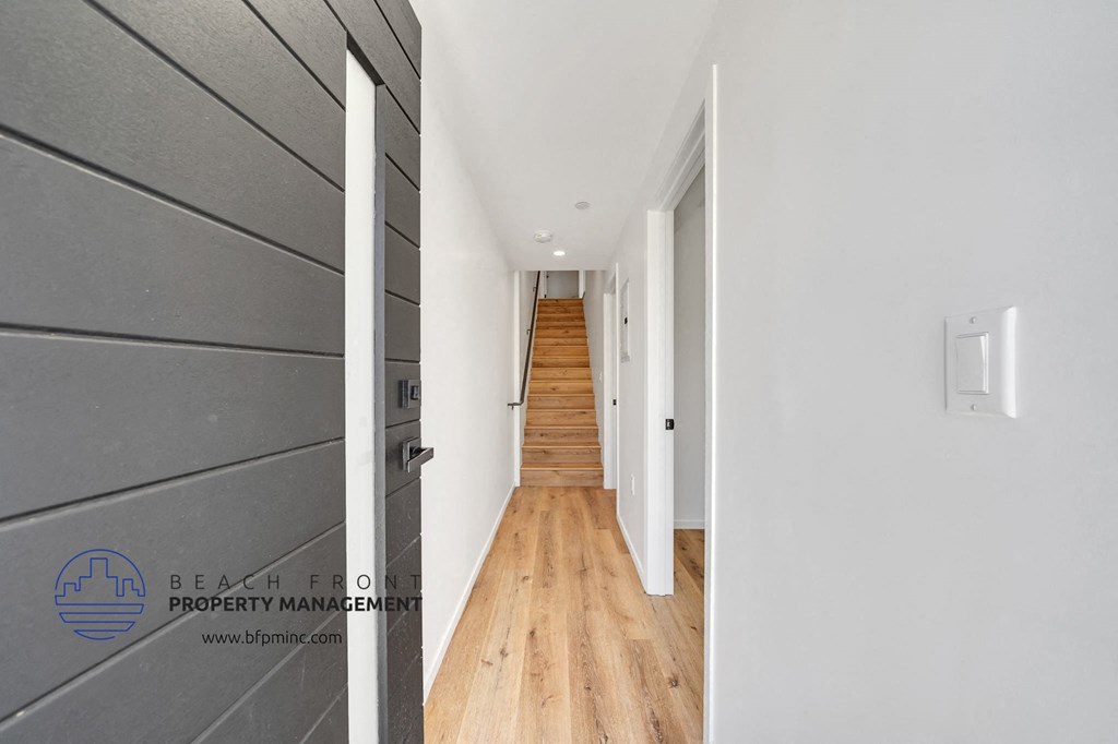 a renovated hallway with wood floors and a staircase