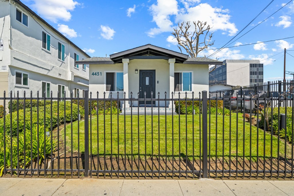 the front of a house with a yard behind a fence