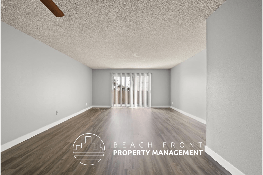 an empty living room with wood flooring and a window