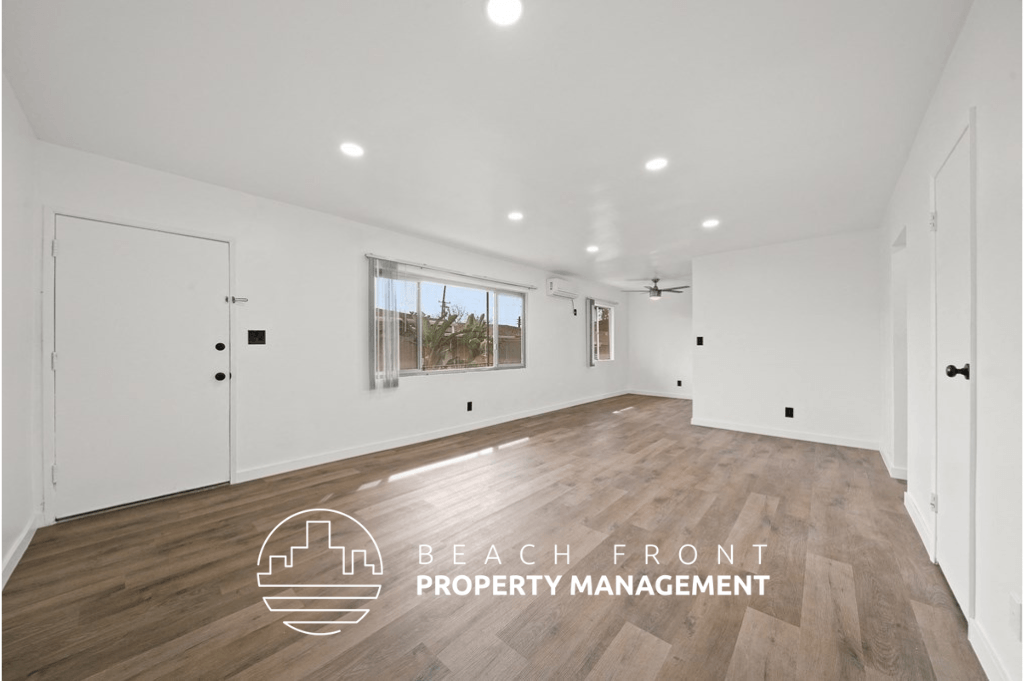 a living room with white walls and wood flooring and a window