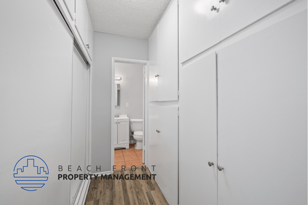a renovated bathroom with white cabinets and a door to the shower