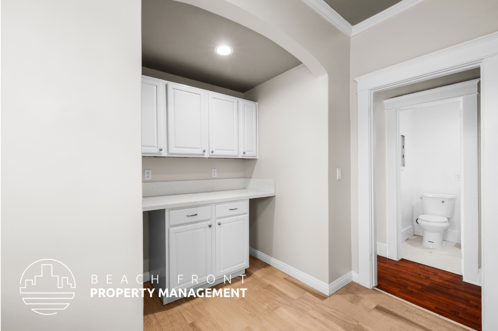 a renovated bathroom with white cabinets and a white toilet and a wooden floor