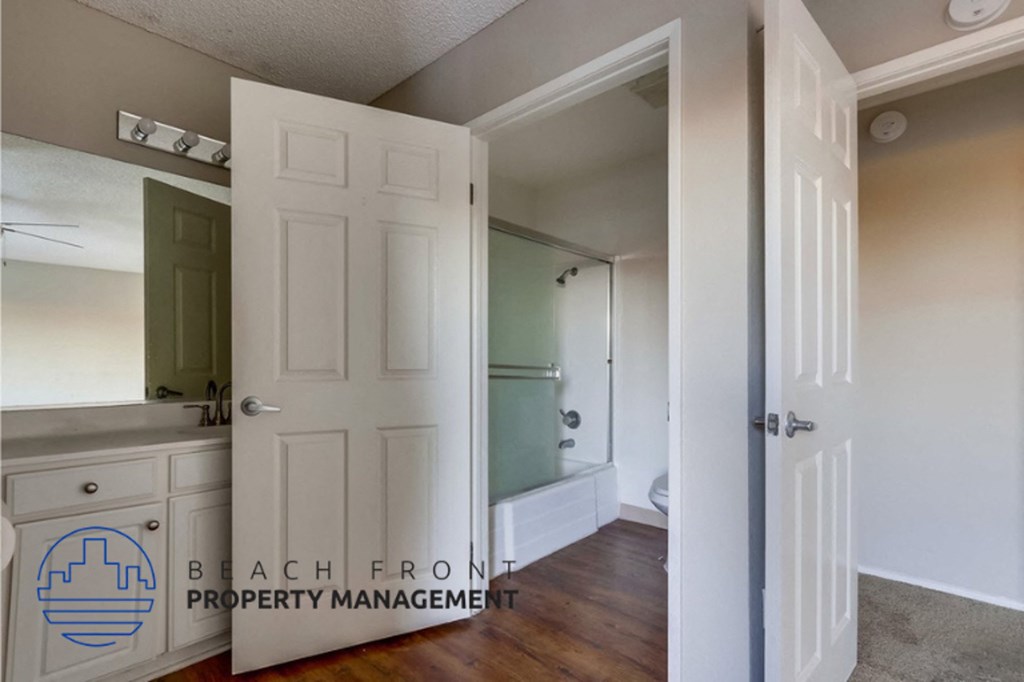 a bathroom with a shower and a sink and a white door