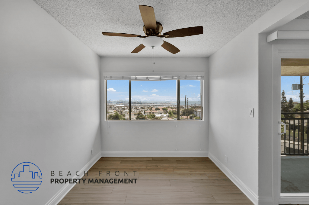 an empty living room with a ceiling fan and a window