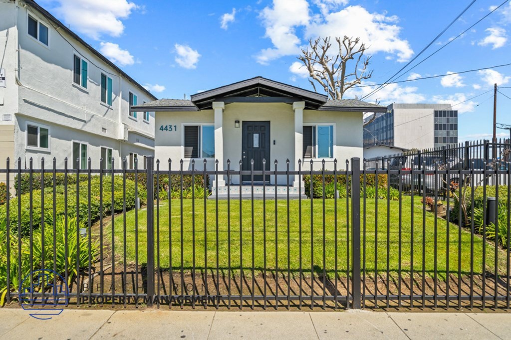 the front of a house with a yard behind a fence