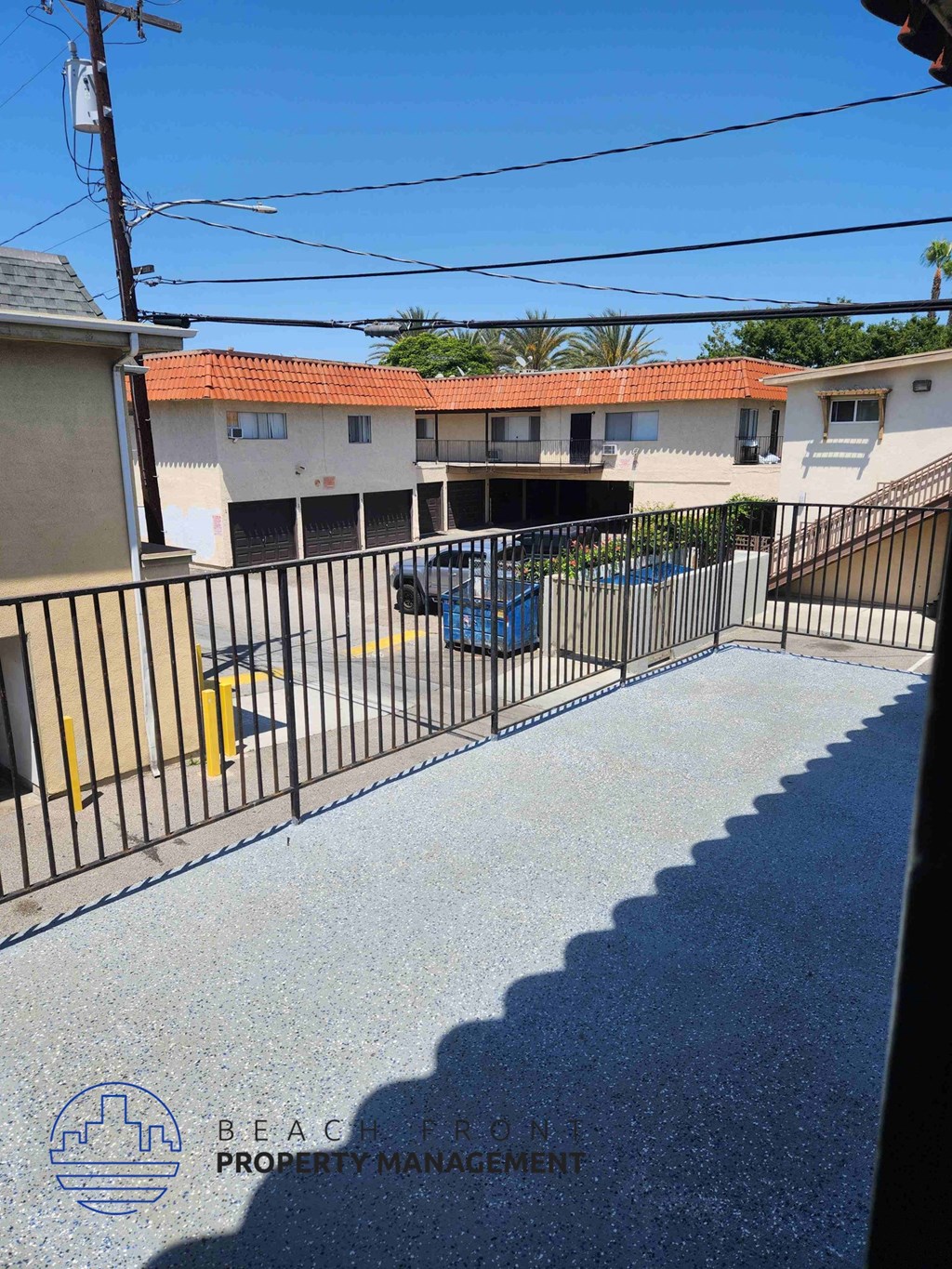 A view of a street with a fence and a sign for Beachfront Property Management.