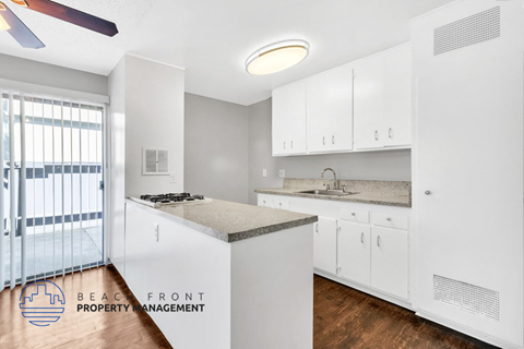 A kitchen with white cabinets and a countertop with a sink.