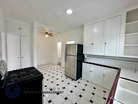 A kitchen with white cabinets and a black fridge.