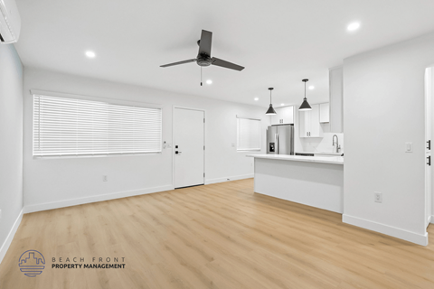 A spacious room with a ceiling fan and pendant lights.