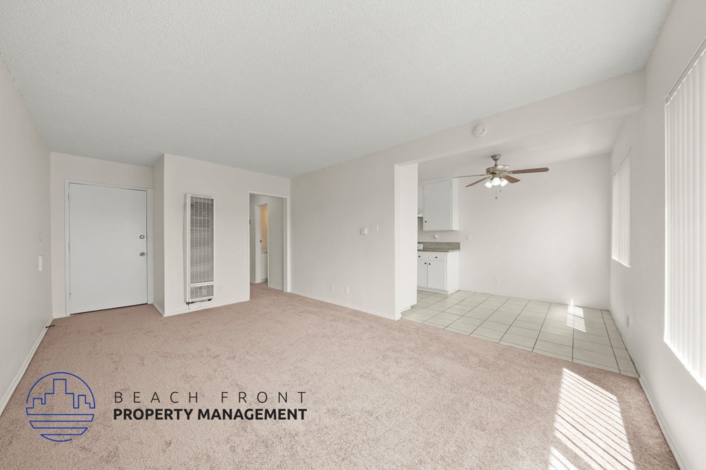 A spacious room with a ceiling fan and a logo for Beach Front Property Management.
