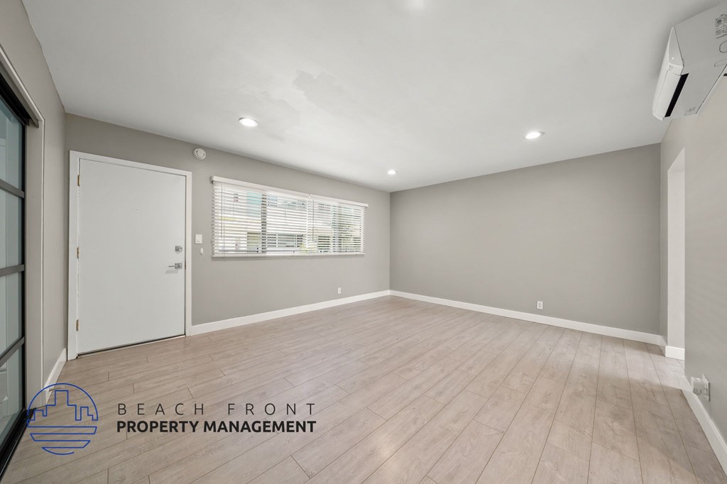 A spacious room with wooden flooring and a white door.